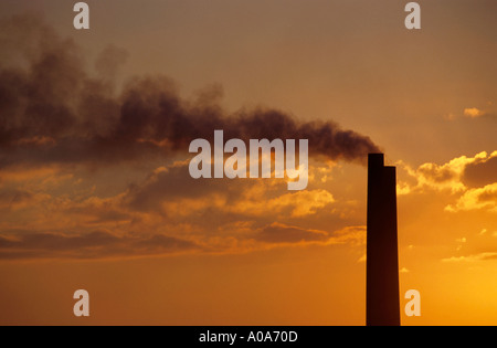Silhouette of an industrial smoking chimney at a power plant at sunset Stock Photo