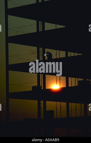 Construction worker does welding on a high rise building at sunrise Stock Photo