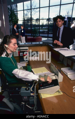 Receptionist with physical handicap greets people at corporation in Virginia Stock Photo