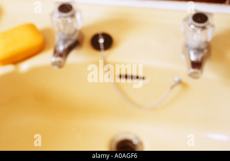 Defocussed wash basin showing taps plug plughole and soap Stock Photo