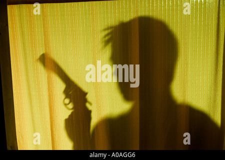 Man holding a gun and hiding behind a curtain Stock Photo