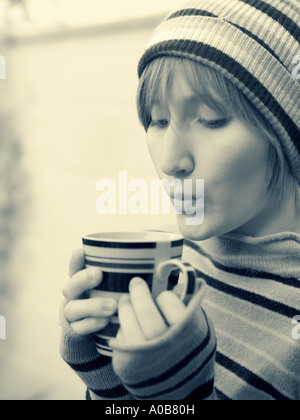 Young woman outdoors blowing on hot drink Stock Photo