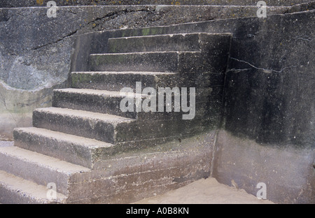 Squat flight of concrete steps from white sandy beach to promenade marred by brutal design and stains and cracks Stock Photo