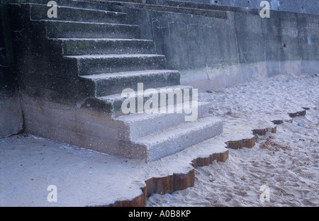 Squat flight of concrete steps from white sandy beach to promenade marred by brutal design and stains and cracks Stock Photo