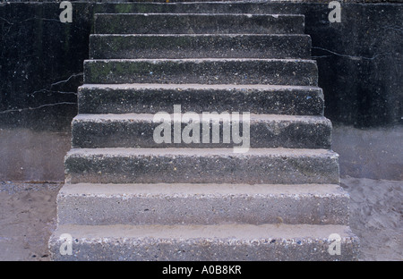 Squat flight of concrete steps from white sandy beach to promenade marred by brutal design and stains and cracks Stock Photo