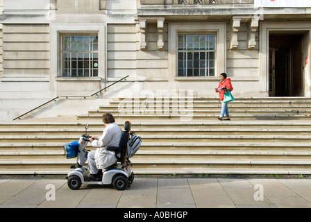 Woman in mobility scooter at foot of steps of Hackney Town Hall, London, England UK Stock Photo