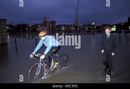 Commuters walk and cycle home through floods in centre of Worcester after city floods England Stock Photo