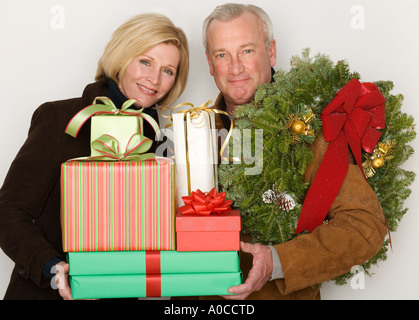 Couple holding Christmas gifts and wreath Stock Photo
