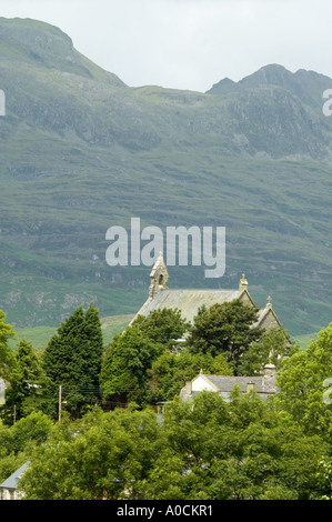 Distant view of church amongst green trees with mountains in background Stock Photo