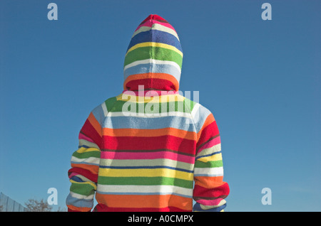 Young woman wearing hooded sweater standing outdoors rear view Stock Photo