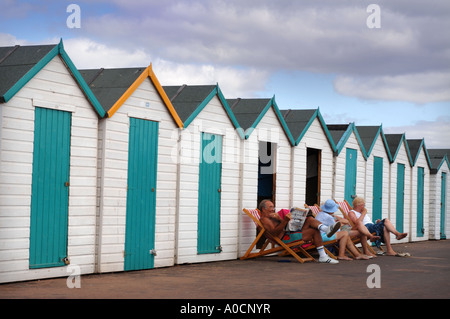 TWO RETIRED COUPLES OUTSIDE THEIR BEACH HUTS ON THE PROMENADE AND MARINE PARADE AT PAIGNTON DEVON UK Stock Photo