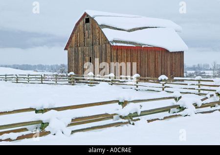 Barn with fence and snow slipping on roof Near Halfway Oregon Stock Photo