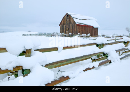 Barn with fence and snow slipping on roof Near Halfway Oregon Stock Photo