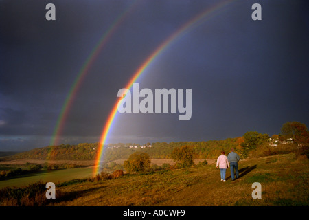 Vivid double rainbow set against dark clouds with a couple observing Kent England UK. Stock Photo