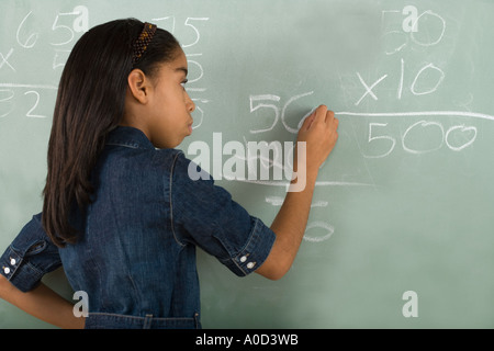 Girl writing on chalkboard Stock Photo