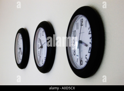three office wall clocks  set at different times Stock Photo