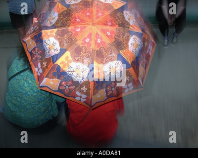 two people huddled together under an umbrella in the pouring rain or ...