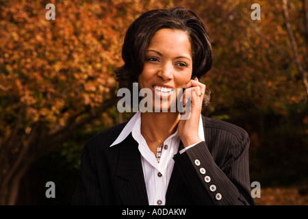 African American business woman talks on cell phone with laptop computer outdoors Stock Photo