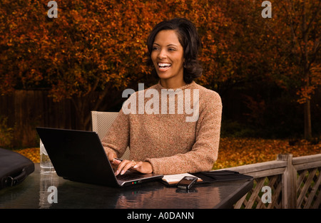 African American businesswoman in casual clothes working with a laptop computer outside in her back yard Stock Photo