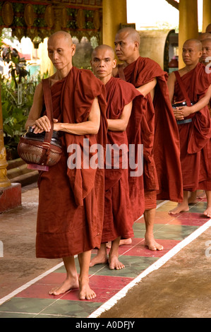 Stock photograph of Buddhist monks with their begging bowls awaiting meal time at Kha Khat Wain Kyaung at Bago in Myanmar 2006 Stock Photo