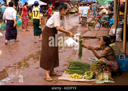 Stock photograph of an old woman buying beans in the market on a wet day at Bago in Myanmar 2006 Stock Photo