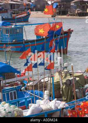 Vietnam Nha Trang city Cai River fishing boats flying national flags alongside buoys with red pennants Stock Photo