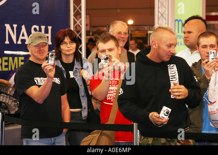 Group of men at an exhibition using digital compact cameras. Stock Photo