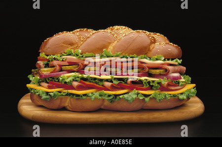 Submarine or hero sandwich, multi-layered with lettuce, tomato, pickles, cheeses and various sliced meats on sesame seed bun Stock Photo