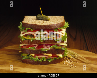 Sandwich, ham turkey, cheese, lettuce, tomato, bacon, pickle, on whole wheat bread Stock Photo
