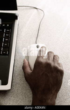 Closeup of mans hand on mouse with laptop computer Stock Photo