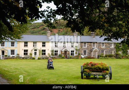 Row of traditional terraced cottages Beddgelert Gwynedd North Wales UK man and dog motorised wheel chair Stock Photo