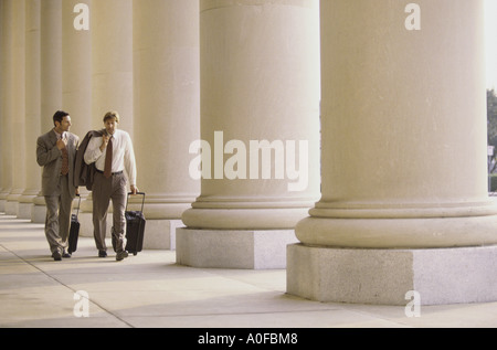 Two businessmen walking side by side, talking Stock Photo - Alamy