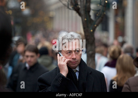 Man uses mobile phone on Oxford Street, London Stock Photo