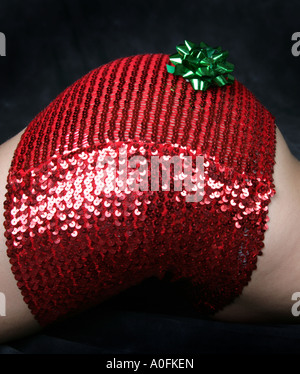 A Womans Bottom in a Red Shiny Skirt and Green Christmas Decoration Stock Photo