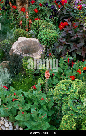 Chelsea FS 1997. Design: Fiona Lawrenson. Drought tolerant plants. Boxwood. Nicotiana. Euphorbia. Verbascum. Peony. Stone mortar Stock Photo