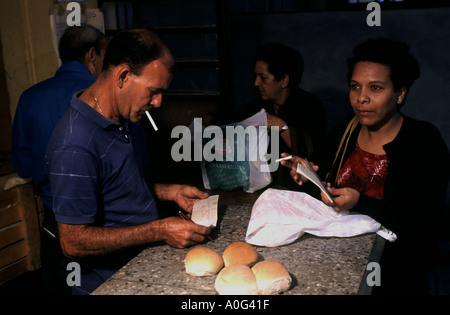 A Cuban woman in Havana buying bread and other basic commodities at a government run and controlled ration shop in Havana Cuba Stock Photo