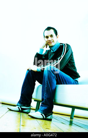 Young man sitting on a sofa and looking down at the camera Stock Photo