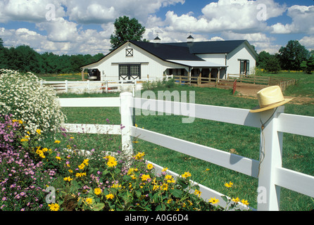 Picturesque white barn as seen from house with white rail fence and garden straw hat, Midwest USA Stock Photo