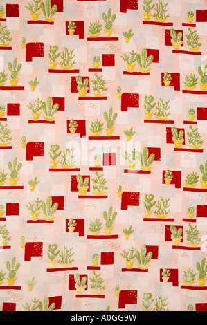 Mad 60s fabric depicting cacti and succulents in yellow plant pots on a background of red grey and pink geometric shapes Stock Photo