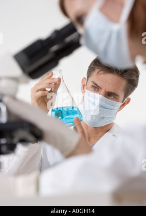 Scientists with microscope and blue liquid Stock Photo