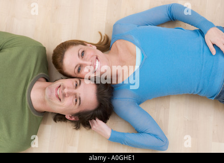 Smiling couple lying on wood floor Stock Photo