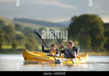 Couple paddling inflatable canoe on lake Stock Photo