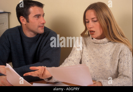 young couple sitting at table having discussion over papers Stock Photo