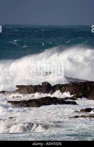 Powerful waves crash against jagged rocks, creating a dramatic coastal ...