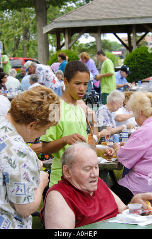 Black teenage male and female providing help at a Seniors July 4th picnic Stock Photo