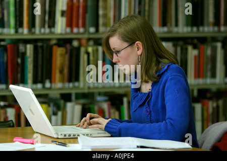 Student young woman working on a laptop in a library Student young woman working in a library at an assignment on a given topic Stock Photo