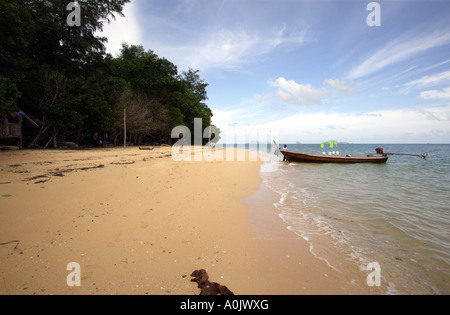 A quiet beach on the island of Bu Bu in Southern Thailand A long boat waits in the shallow water This is one of the smallest islands and has no inhabitants just holiday bungalows Stock Photo