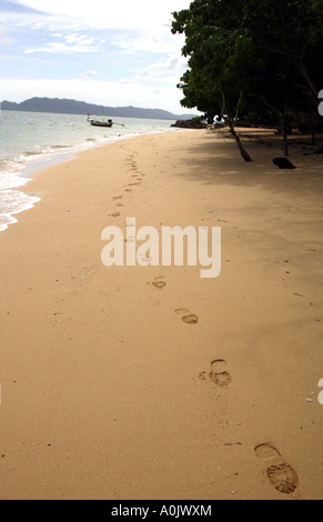 A quiet beach on the island of Bu Bu in Southern Thailand Footprints lead across the sand to a boat in the shallow waters This is one of the smallest islands and has no inhabitants just holiday bungalows Stock Photo