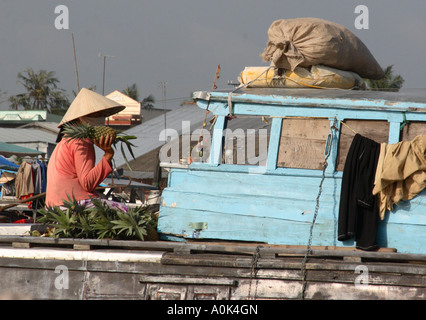 A boatperson selling pineapple in the floating markets in the Mekong Delta, Vietnam Stock Photo