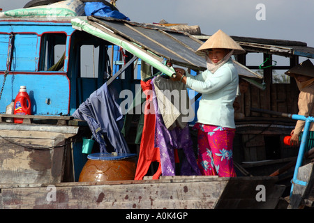 A woman hanging out her laundry on her boat in the floating markets in the Mekong Delta in Vietnam Stock Photo